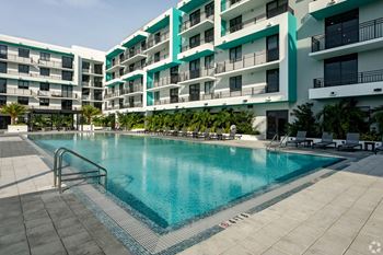 A swimming pool in the rooftop patio with apartment balconies directied